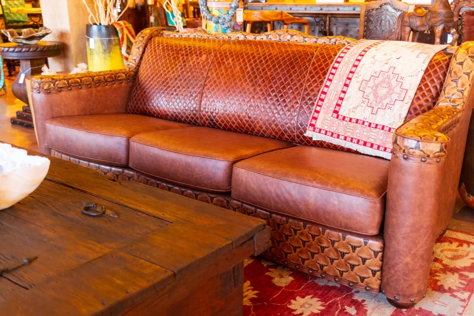 Tooled leather sofa, woven throw and wooden coffee table in the showroom
