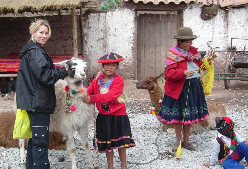 A visitor with a Peruvian family in traditional dress and their animals