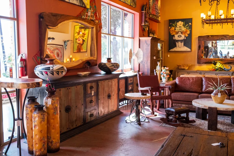 Sunlit showroom with a wooden console, pottery, wall art and leather seating