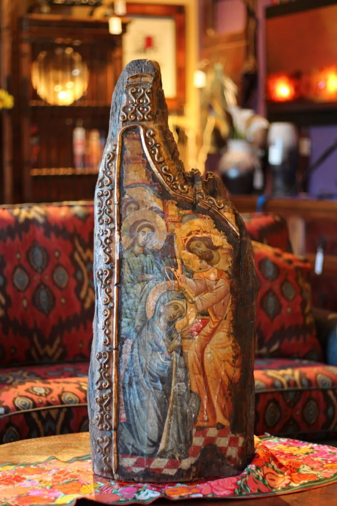 Icon of robed figures with gold halos, painted on a carved wood stump