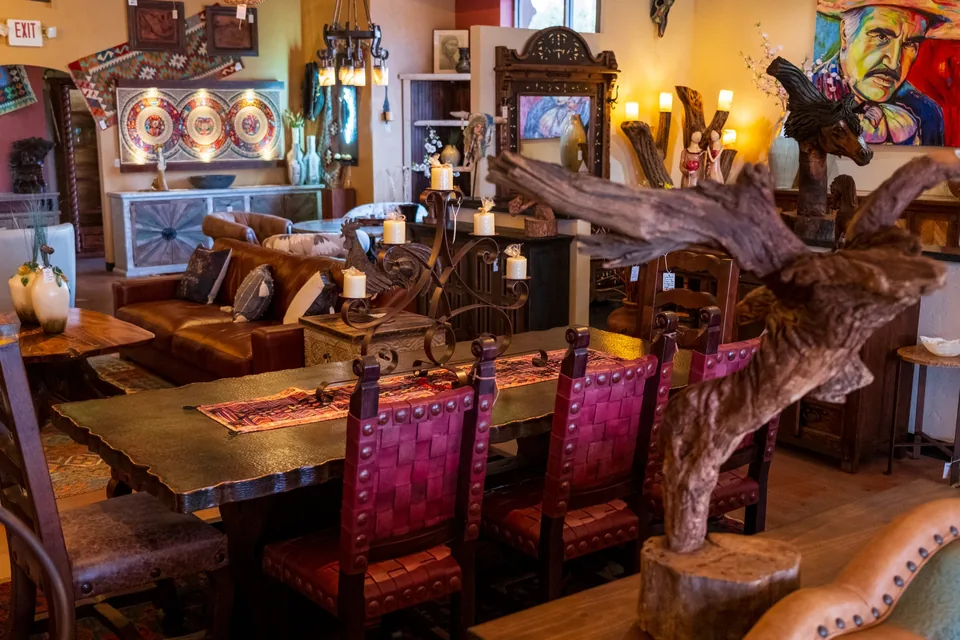Rustic dining table and red leather chairs beside a carved wood sculpture
