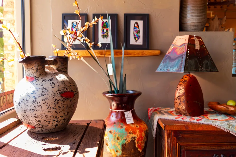 Hand-painted pottery vases and a table lamp beside a sunny showroom window